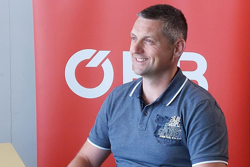 Traktionstechniker der ÖBB sitzt vor ÖBB-Banner